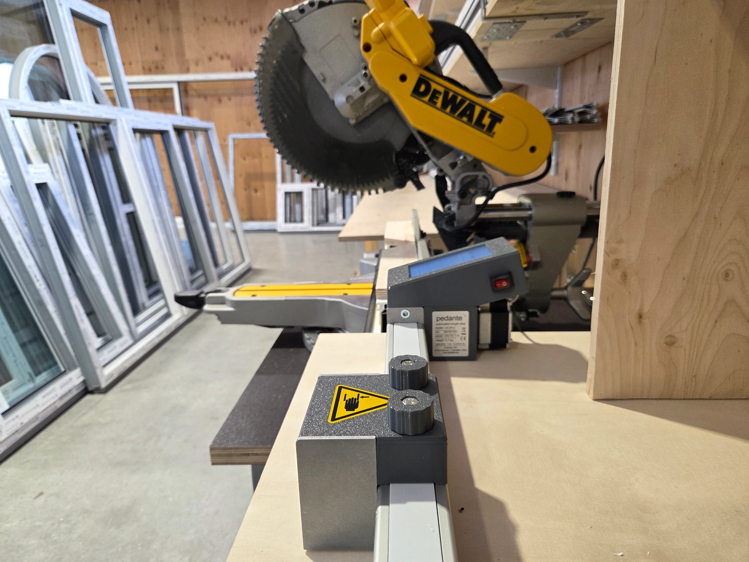 Butée numérique pour scie à onglet Pedante montée sur une station de sciage dans un atelier de fabrication de fenêtres en PVC